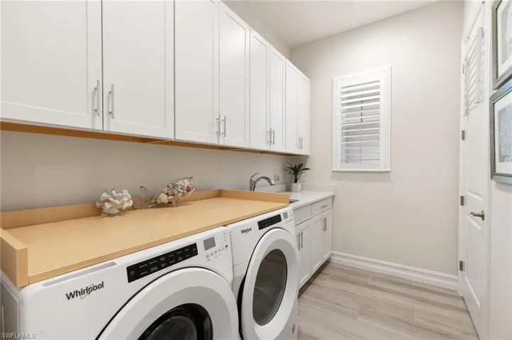 Washroom featuring light wood-type flooring, washing machine and clothes dryer, and cabinet space
