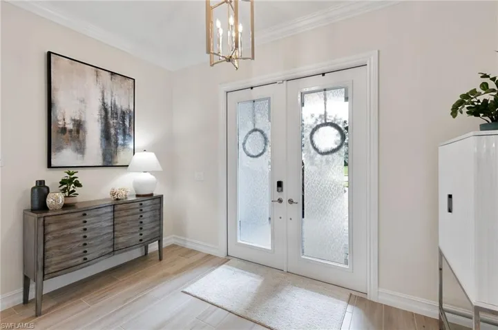 Entrance foyer featuring french doors, ornamental molding, wood finish floors, and a chandelier