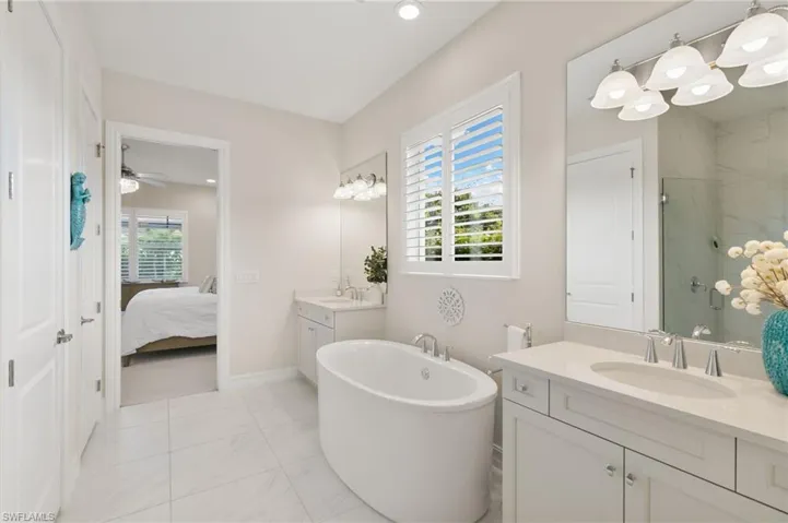 Bathroom featuring a marble finish shower, a soaking tub, two vanities, light marble finish floors, and recessed lighting