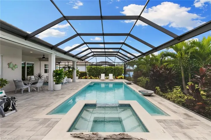 View of swimming pool with a pool with connected hot tub, glass enclosure, a sunroom, a ceiling fan, and a patio area