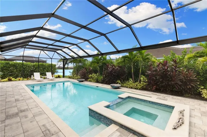 View of swimming pool featuring a lanai, a sunroom, a water view, a pool with connected hot tub, and a patio area