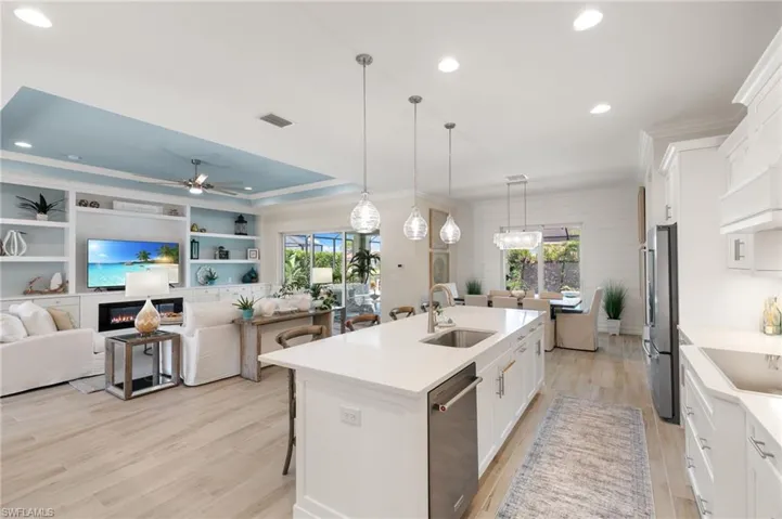 Kitchen featuring a kitchen breakfast bar, open floor plan, white cabinets, a center island with sink, and recessed lighting