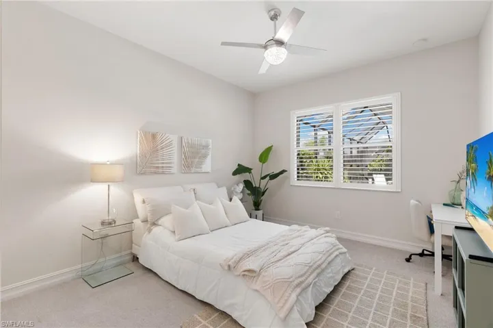 Bedroom featuring light colored carpet, ceiling fan, and an office area