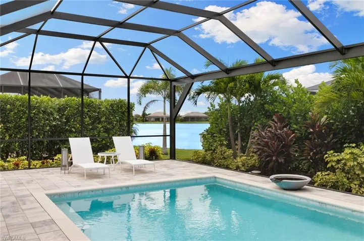 Outdoor pool with a lanai, a water view, a sunroom, and a patio area