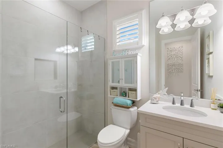 Bathroom featuring a stall shower, vanity, and a chandelier