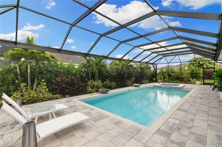 View of swimming pool featuring glass enclosure, a sunroom, and a pool with connected hot tub