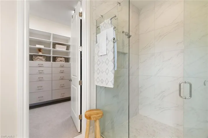Bathroom with a marble finish shower and light carpet