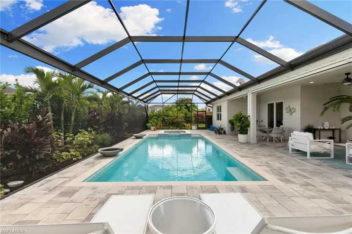 View of swimming pool featuring ceiling fan, a sunroom, a lanai, a pool with connected hot tub, and a patio