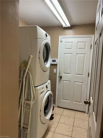 Washroom with laundry area, light tile patterned flooring, and stacked washer / drying machine