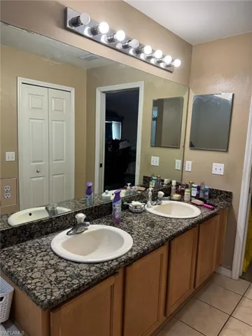 Bathroom with double vanity, tile patterned floors, and a sink