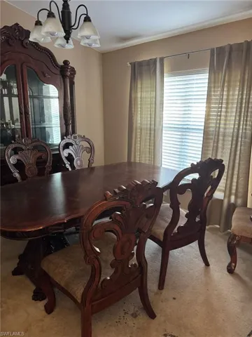 Carpeted dining space with an inviting chandelier and a healthy amount of sunlight