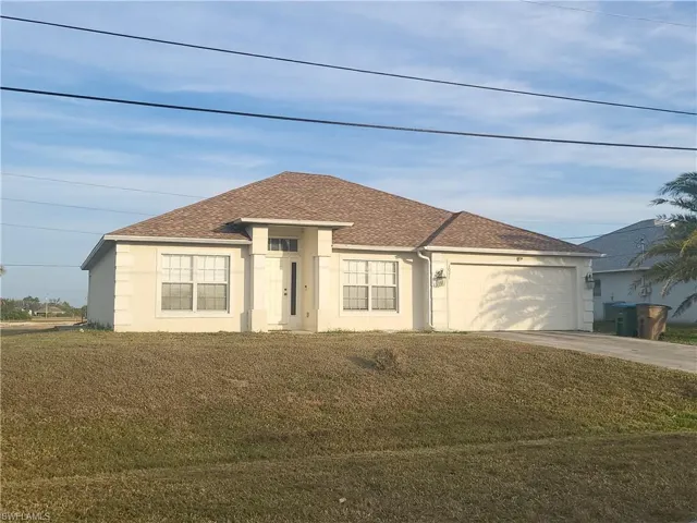 View of front facade featuring a garage and a front lawn