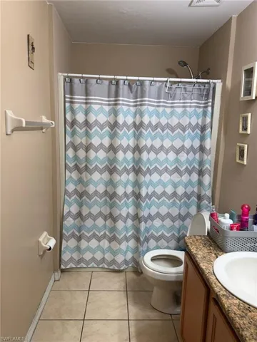 Bathroom with tile patterned floors, visible vents, toilet, a shower with curtain, and vanity