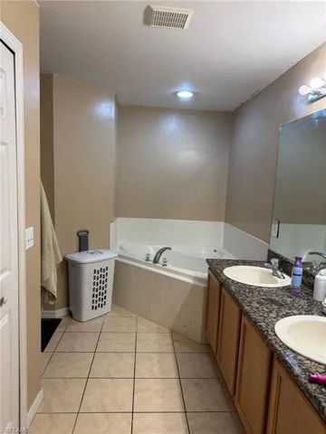 Bathroom featuring tile patterned flooring, visible vents, a bath, and a sink