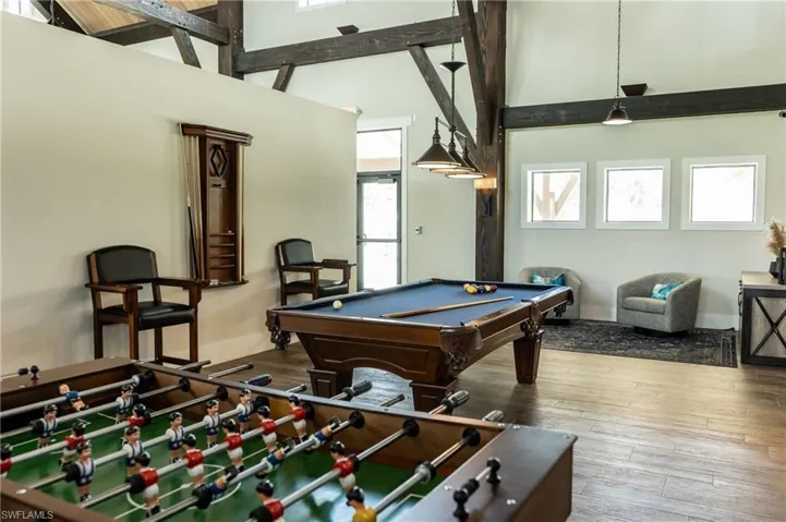 Rec room featuring billiards table, healthy amount of natural light, a towering ceiling, and wood-type flooring