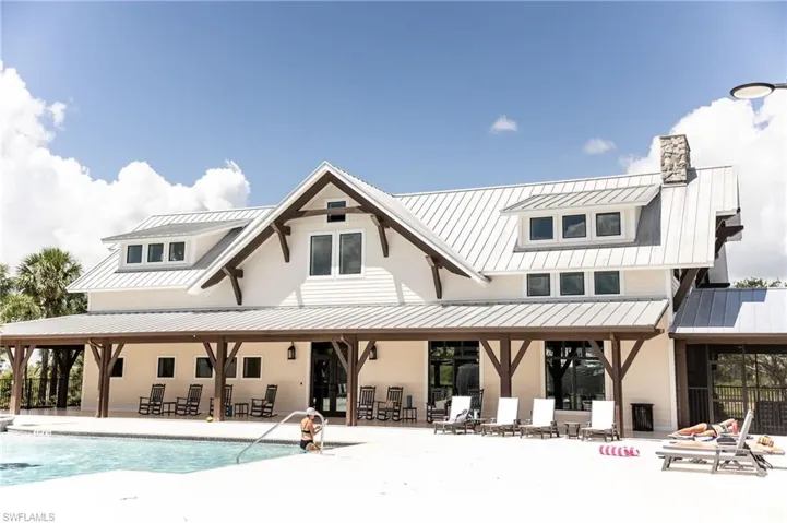 Back of property featuring a patio, a chimney, a metal roof, and a community pool