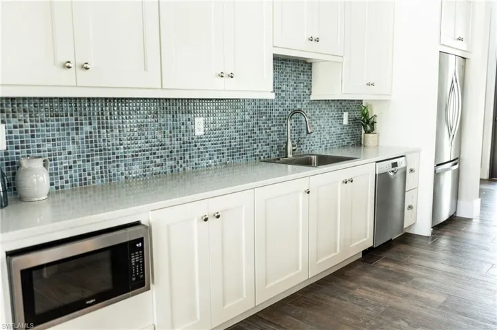 Kitchen with appliances with stainless steel finishes, white cabinetry, and backsplash