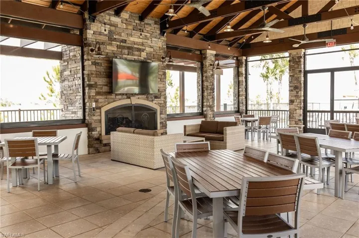 Dining space with an outdoor stone fireplace, a wood ceiling with exposed beams, and high vaulted ceiling