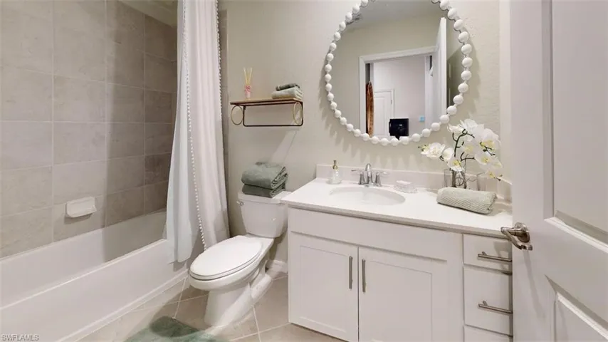 Full bath with vanity, shower / bath combo with shower curtain, and light tile patterned floors
