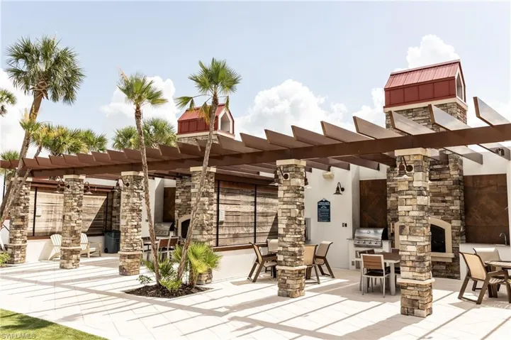 Rear view of property featuring a fireplace, stone siding, and a pergola