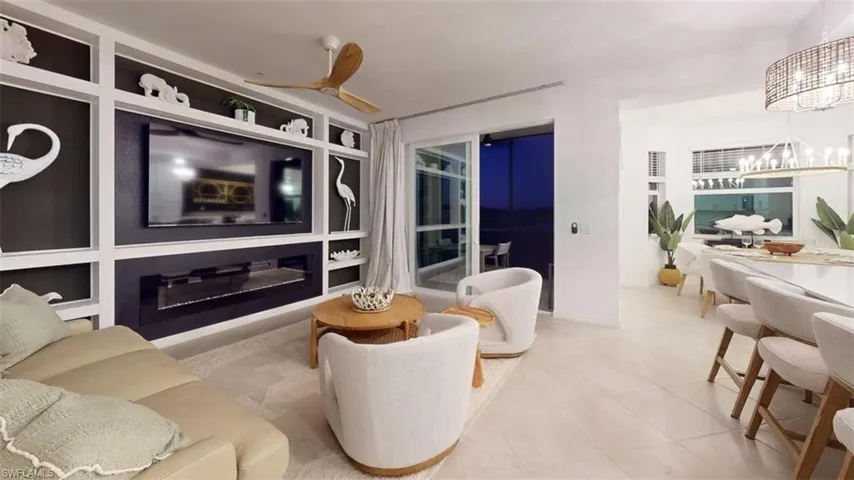 Living room with built in features, light tile patterned floors, and ceiling fan