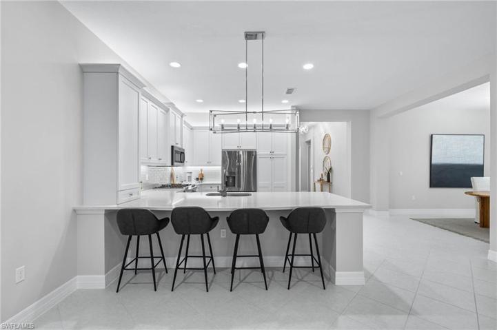 Large peninsula with upgraded lighting & quartz counters, open to the dining room.