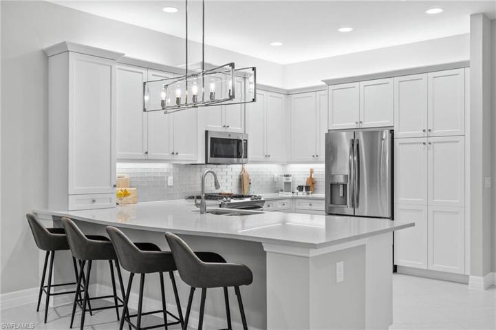 Stainless steel appliances and large peninsula with quartz counters.