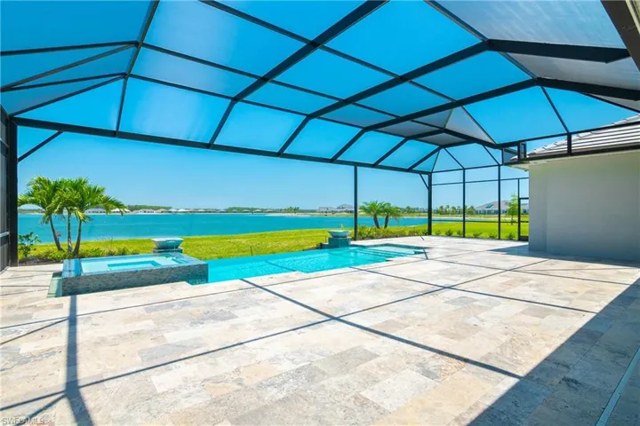 View of swimming pool featuring a water view, an in ground hot tub, a patio area, and glass enclosure