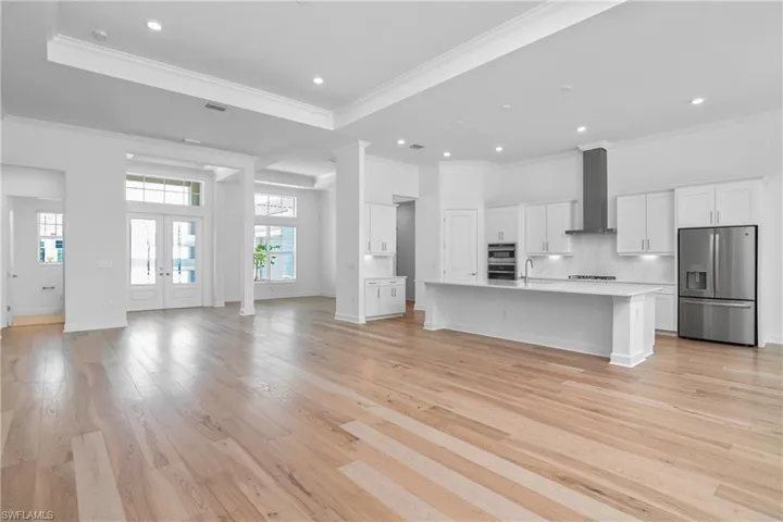 Unfurnished living room with sink, light hardwood / wood-style flooring, ornamental molding, and french doors