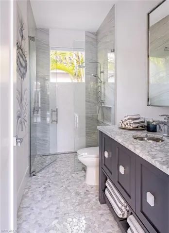 Bathroom featuring vanity, toilet, and a shower with door