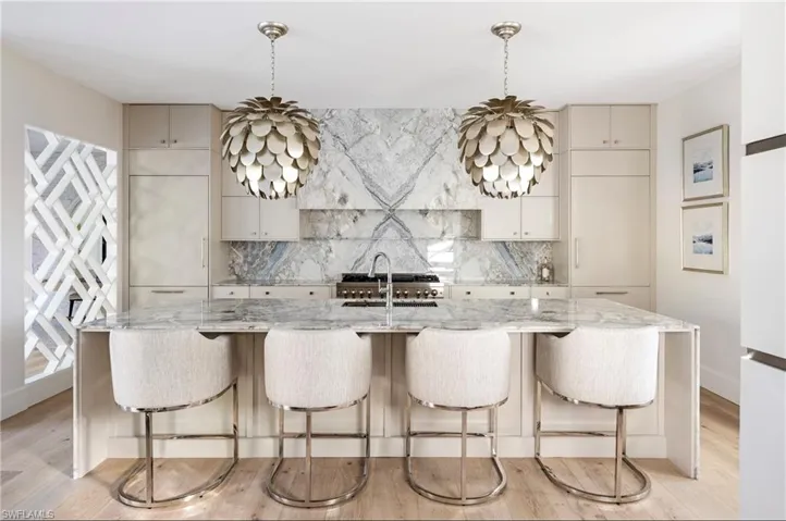 Kitchen featuring light stone countertops, sink, a spacious island, and decorative light fixtures