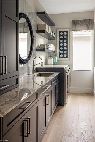 Kitchen featuring sink, light stone counters, separate washer and dryer, and light wood-type flooring