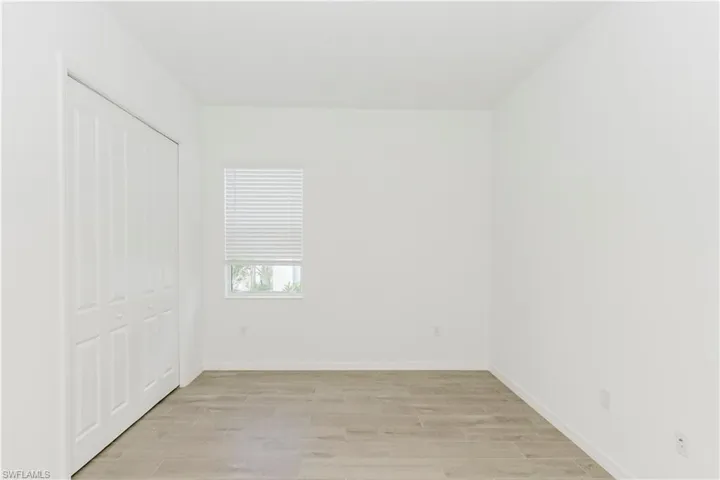 Unfurnished bedroom with light wood-type flooring, baseboards, and a closet