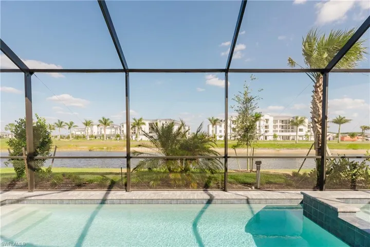 View of pool featuring a lanai, a water view, and a pool with connected hot tub