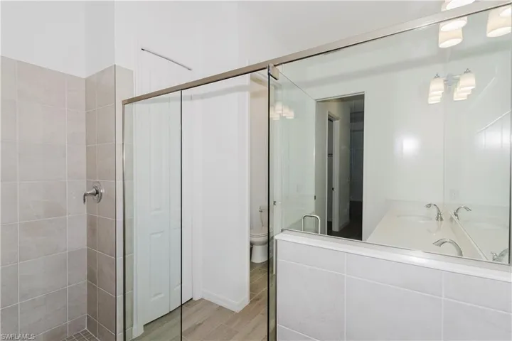 Full bath with a shower stall, toilet, and wood finished floors