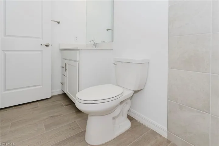 Bathroom with vanity, baseboards, wood finished floors, and toilet