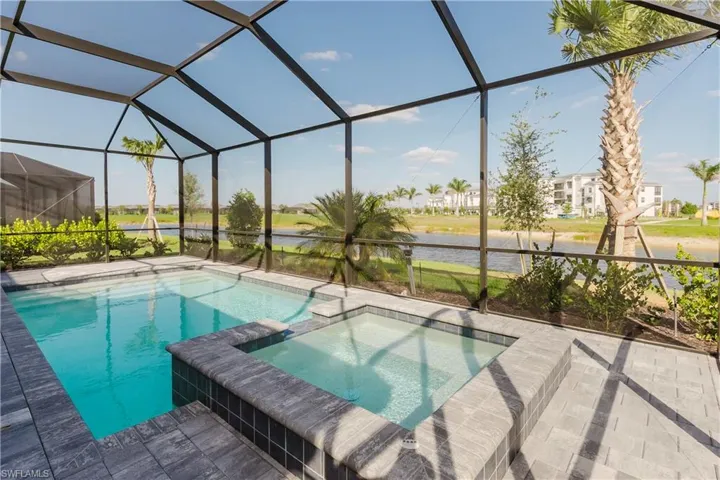 View of swimming pool featuring a patio, glass enclosure, and a pool with connected hot tub