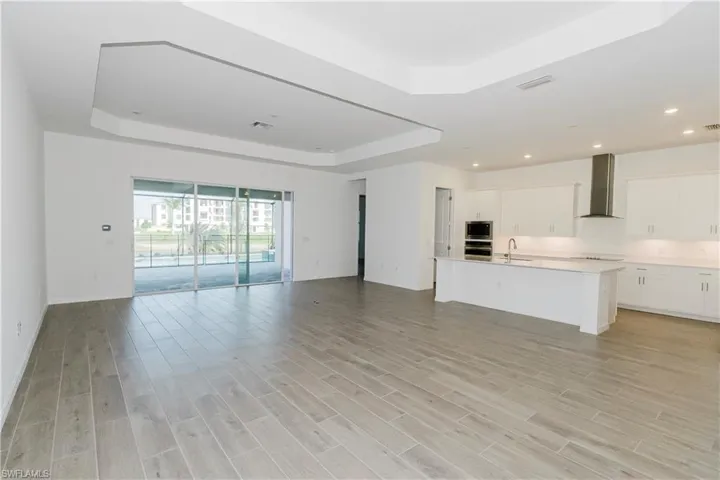 Unfurnished living room with visible vents, a sink, a raised ceiling, and light wood-style flooring