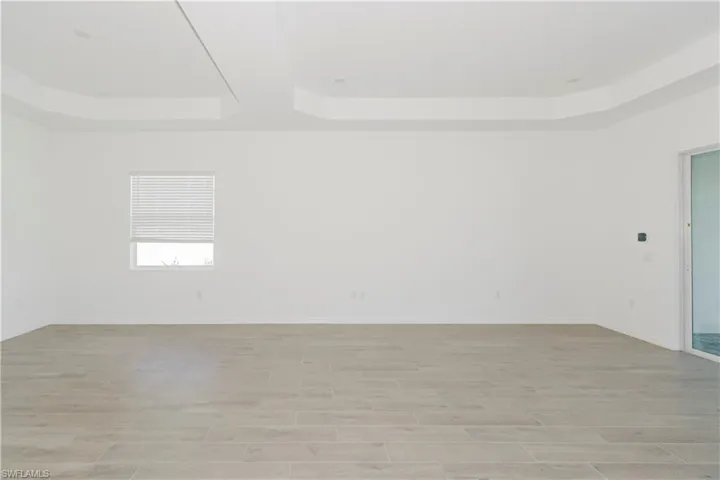 Empty room with light wood-style floors, baseboards, and a tray ceiling