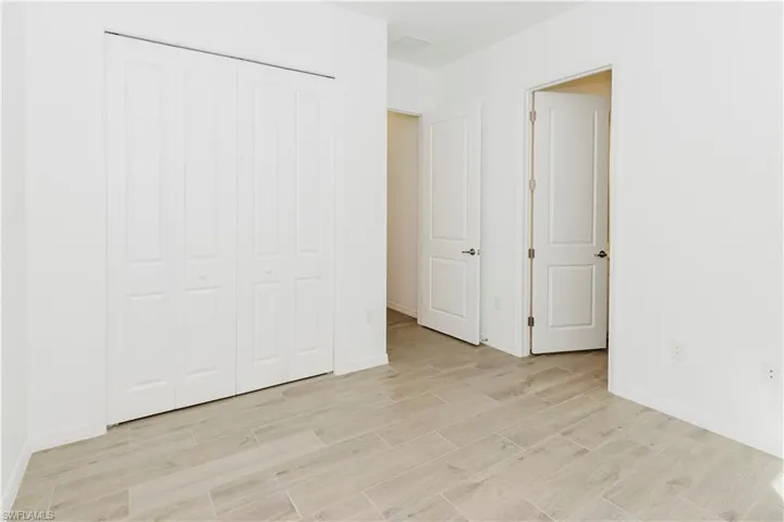 Unfurnished bedroom with light wood-style floors, baseboards, and a closet