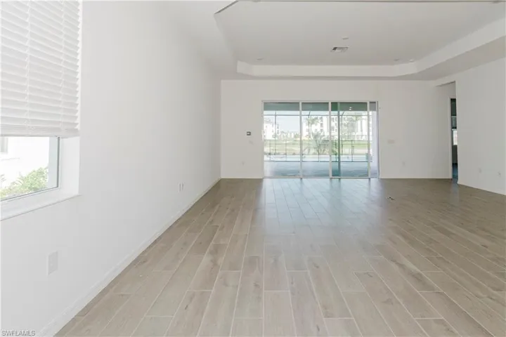 Unfurnished room with a raised ceiling, baseboards, light wood-style flooring, and visible vents