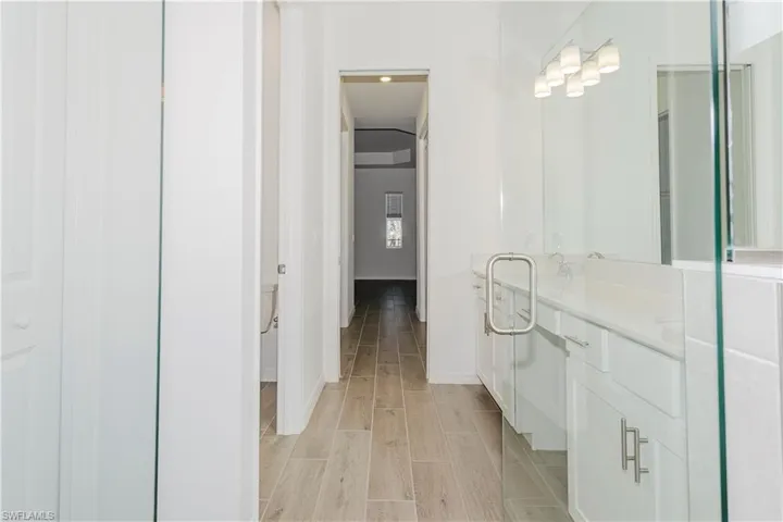 Full bathroom with vanity, baseboards, and wood finished floors