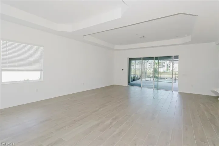 Spare room with a raised ceiling, baseboards, light wood finished floors, and visible vents
