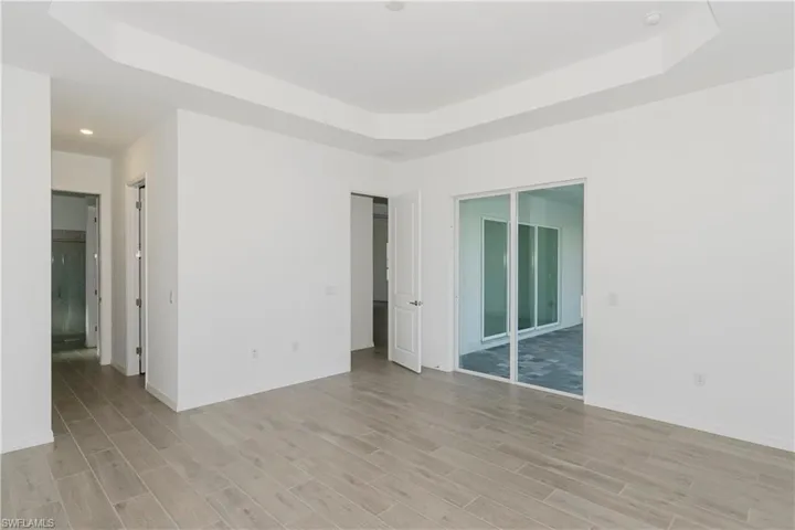 Spare room featuring recessed lighting, baseboards, light wood finished floors, and a raised ceiling