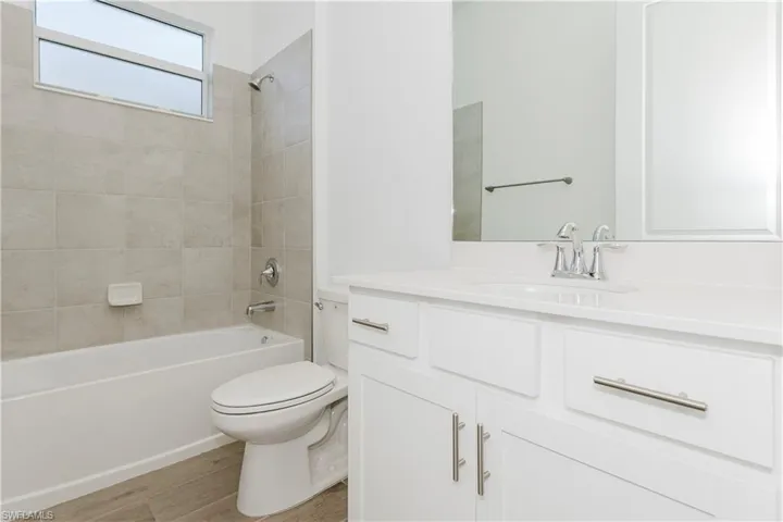 Bathroom featuring shower / bathtub combination, toilet, wood finished floors, and vanity