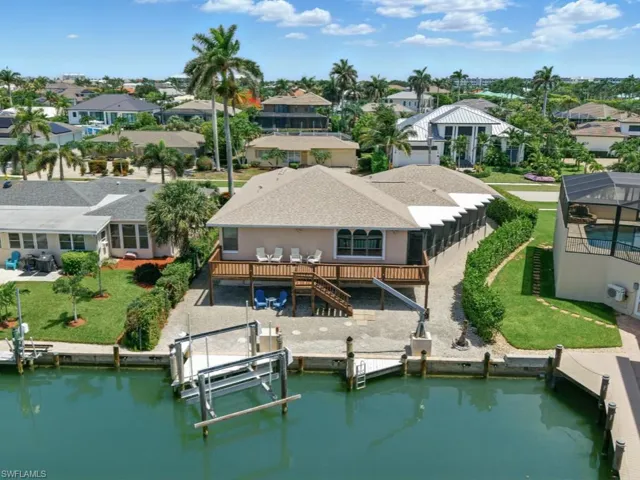 Rear view of property featuring boat lift, a residential view, stairs, and a lawn