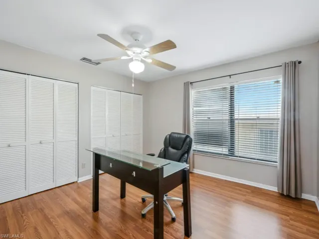 Office space with a ceiling fan and wood finished floors and double closets