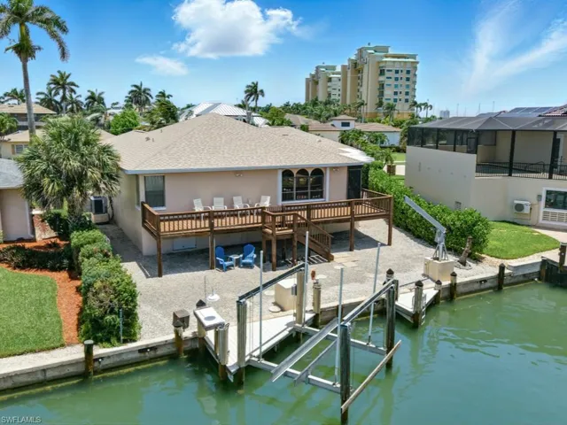 Rear view of house featuring 12,000 lb boat lift, a deck with water view, and southwest exposure