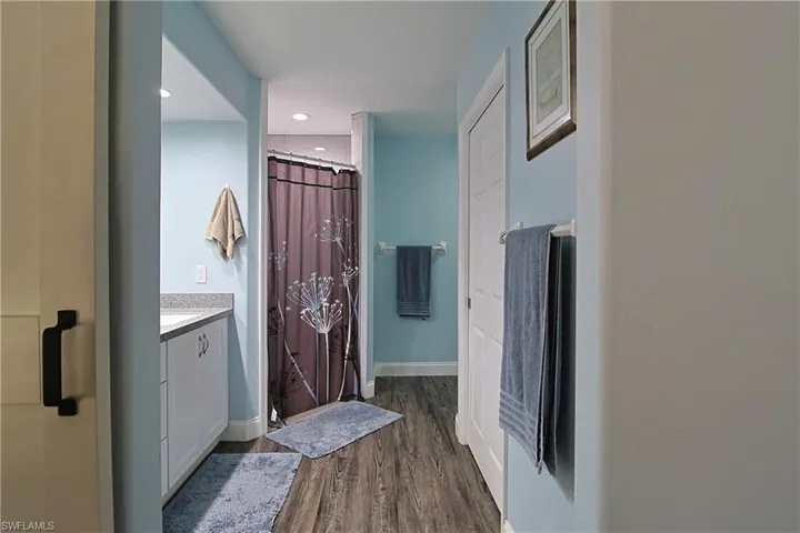 Bathroom with a stall shower, vanity, dark wood-style flooring, and recessed lighting