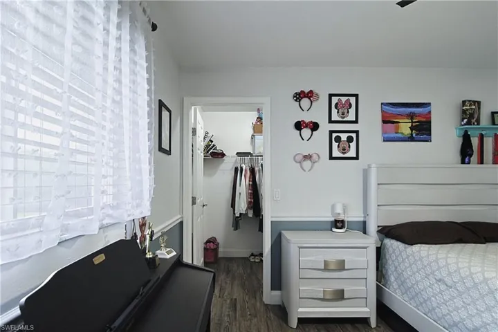 Bedroom featuring a walk in closet, dark wood-style flooring, and ceiling fan